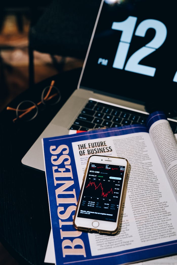 Services-01 Laptop and smartphone displaying business analytics and cryptocurrency data on a desk with a magazine.